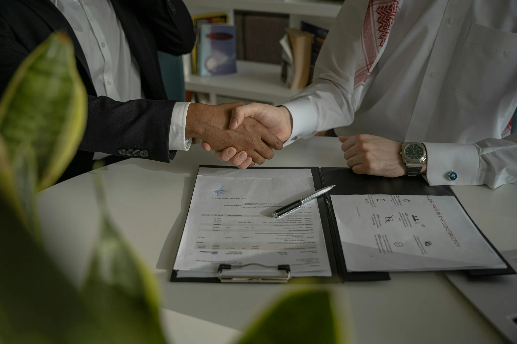 Business partners shake hands over signed documents